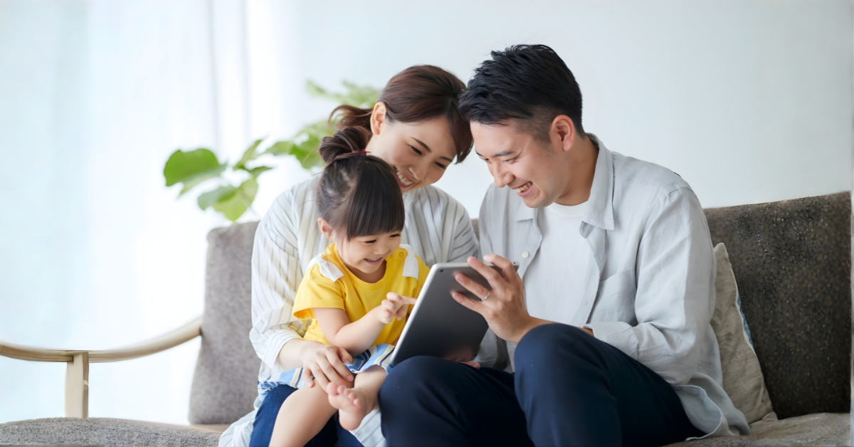 Parents and child smiling while using a tablet together at home